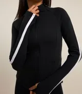 Campera deportiva negra de microfibra con ajuste al cuerpo, cuello alto, cierre por cremallera, bolsillos con cierre y raya contrastante blanca de hombro a puño.