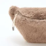 Riñonera de diseño compacto confeccionada en piel sintética de pelo largo color gris topo. Cuenta con un compartimento principal con cierre metálico y tiradores de cordón.