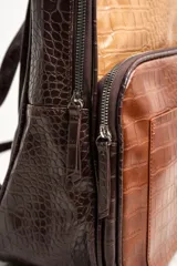 Mochila marrón con estampado de piel de cocodrilo, con cierre superior y bolsillo frontal con cierre.