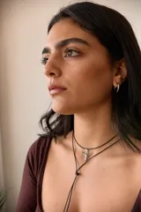 Collar con dije de acero quirúrgico en forma de cráneo de toro, montado sobre un cordón marrón.