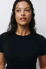 Remera básica de algodón negro, de corte entallado, cuello redondo y mangas cortas.