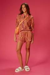 Short de playa con estampado geométrico en tonos naranja, amarillo y rosa. Cintura elástica y ribete rosa.