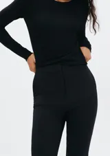 Pantalón de sastre negro de corte ajustado y tobillero, de tiro alto con cierre frontal.