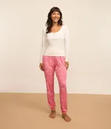 Conjunto de pijama largo de dos piezas, compuesto por una remera de mangas largas con cuello redondo y botones, y un pantalón con cintura elástica y puños ajustados. El pantalón tiene estampado de lazos, bebidas y espejos.