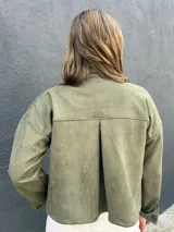 Sobrecamisa verde de gamuza sintética, estilo chaqueta de media estación, con bolsillos frontales con solapa y cierre de botones oscuros.