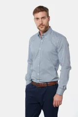 Camisa de manga larga con cuello abotonado y estampa a cuadros en tonos de azul y blanco. Presenta un bolsillo aplicado en el pecho con detalle de bordado y cierre frontal con botones.