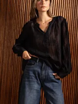 Blusa negra de tela liviana con bordado floral tono sobre tono. Presenta escote en V con detalle bordado en el frente, mangas largas con leve volumen y puños ajustados.
