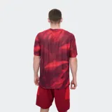 Remera deportiva Umbro modelo Press, de color rojo con un estampado abstracto en tonos más oscuros, cuello redondo y manga corta. Incluye el logo de la marca en el pecho y el escudo del Club Nacional de Football.