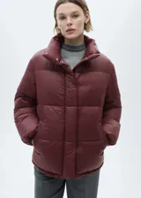 Campera puffer de cuello alto con diseño acolchado, cierre oculto de cremallera y botones a presión, y bolsillos laterales.