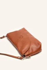 Cartera bandolera color beige, confeccionada en 100% cuero, con solapa redondeada, detalle de flor grabada y correa larga ajustable.