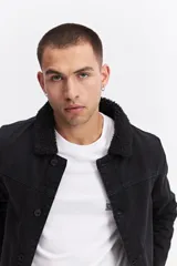 Campera de jean con interior de corderito, cuello clásico y cierre frontal con botones metálicos. Presenta un diseño de denim azul con costuras reforzadas y bolsillos laterales.