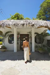 Falda larga tejida color marrón con brillo metálico, corte al cuerpo, abertura alta en la pierna y recortes laterales con cordones ajustables.