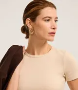 Blusa color beige de mangas cortas, confeccionada en tejido rib con textura acanalada y cuello redondo.