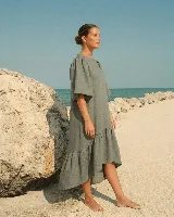 Vestido largo de lino color beige, con mangas abullonadas y volado inferior asimétrico, más largo en la parte trasera.