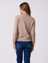 Buzo de tejido de punto color beige, con cuello alto y mangas largas. Presenta un diseño de calce ajustado con puños y ruedo acanalados.