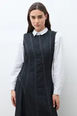 Maxi vestido sin mangas de denim oscuro, con corte al cuerpo en el torso y falda acampanada que cae hasta el tobillo. Presenta costuras visibles en contraste que definen los paneles del vestido.