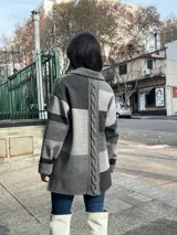 Camisa de lana con diseño de bloques de color en tonos grises, cuello clásico, cierre frontal con botones y bolsillos frontales con detalles en cuero sintético.