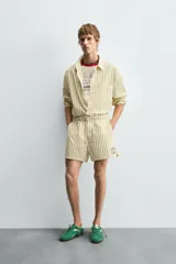 Shorts de hombre confeccionados en algodón con estampado de rayas verticales amarillas y blancas. Presenta cintura elástica, bolsillos frontales y un pequeño bordado de un pez en la parte inferior derecha.