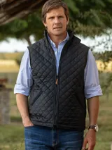 Chaleco capitoneado negro de hombre con diseño acolchado en rombos, cuello alto y cierre frontal con cremallera.