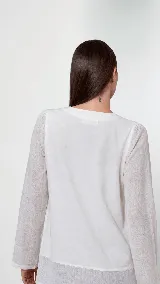 Remera de manga larga confeccionada en una combinación de lino y algodón. Presenta escote en V, diseño con cortes frontales y detalle de logo bordado. Posee un calce cómodo con aberturas laterales en el ruedo.