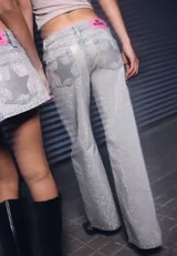 Jean de corte recto y tiro bajo, confeccionado en denim con acabado brillante. Presenta diseño clásico de cinco bolsillos, cierre frontal con cremallera y botón metálico, y trabillas en la cintura.