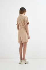 Mono corto color beige con cuello camisero, mangas cortas con dobladillo, cierre frontal con botones, cinturón de tela y bolsillos delanteros.