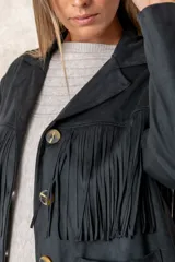 Chaqueta de gamuza sintética color marrón, con diseño de flecos en el pecho y la espalda. Presenta cierre frontal con botones, cuello camisero y bolsillos cuadrados frontales.