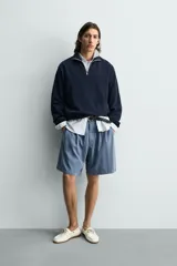 Sudadera regular fit azul marino confeccionada en tejido de algodón con estructura piqué. Cuenta con cuello subido, cierre frontal de cremallera corta y mangas largas con acabados en rib.