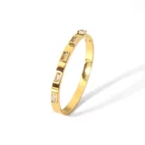 Brazalete rígido dorado con incrustaciones de circonitas rectangulares.