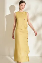 Falda midi verde de lino, con diseño asimétrico, tajito frontal y cierre lateral con botones de madera con ojales bordados.
