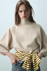 Jersey de punto verde militar, con cuello subido y mangas largas anchas de corte acampanado.