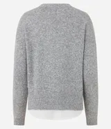 Suéter de punto jaspeado en color gris oscuro, con cuello redondo y mangas largas. Presenta un diseño integrado con una camisa blanca debajo, creando un efecto de capas superpuestas.