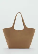 Bolso tipo shopper de tamaño grande, confeccionado en tejido de nylon color tostado. Cuenta con doble asa, cierre de cremallera y un cierre metálico a presión en la parte frontal.