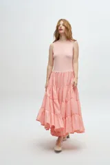 Vestido largo color salmón, con cuerpo ajustado de algodón y falda amplia de rayon, nylon, poliéster y elastano. Presenta un volante plisado en diagonal desde el hombro hasta la cintura.