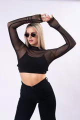 Polera crop de tul negro con cuello alto y mangas largas, confeccionada en tejido traslúcido.