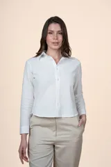 Camisa de algodón color blanco, con cuello camisero, cierre frontal con botones y mangas largas con puños abotonados.