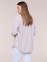 Camisa de lino de la marca Dash, color beige con rayas verticales blancas. Cuenta con cuello camisero, cierre frontal con botones, un bolsillo aplicado en el pecho y mangas largas con sistema de ajuste para arremangar.