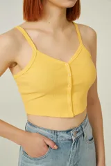 Top amarillo de breteles finos, confeccionado en poliéster de punto canalé, corte al cuerpo, con botones y cuello en V.
