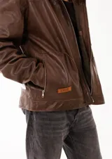 Campera estilo biker de cuero genuino color marrón, con cierre frontal metálico y bolsillos laterales con cierre. Presenta un diseño de corte amplio y estructura robusta.