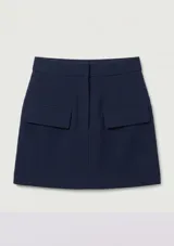 Short pollera azul marino con bolsillos delanteros simulados con solapa y cierre frontal oculto.