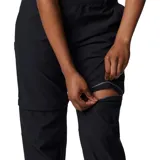 Pantalón técnico convertible en short, color negro, con diseño funcional para actividades al aire libre. Presenta rodillas articuladas, múltiples bolsillos incluyendo uno de seguridad con cierre, presillas para cinturón y dobladillo ajustable. Las piernas son desmontables mediante cierres diferenciados.