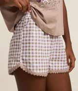 Conjunto de pijama compuesto por una remera de algodón color beige con estampado frontal místico y un short con estampado de cuadros vichy, cintura elástica y detalle de encaje en el ruedo.