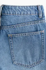 Short de denim de algodón rígido, con diseño de tiro alto y cinco bolsillos. Presenta lavado azul clásico y dobladillo deshilachado.