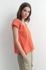 Remera naranja de corte recto, con cuello en V y mangas cortas. Presenta detalle de vainillas en los laterales y en los hombros.