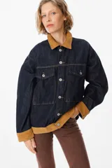 Chaqueta de denim azul oscuro con detalles en pana color tostado en el cuello, puños y ruedo. Presenta cierre frontal con botones metálicos y bolsillos frontales con solapa.