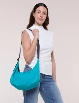 Cartera bandolera color turquesa en forma de medialuna, confeccionada en lona de poliéster. Posee correa ajustable en color negro y cierre superior.