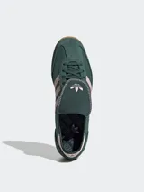 Zapatillas Adidas modelo SL 72 OG LT, de diseño retro inspirado en el running y el fútbol. Presentan un cuerpo de gamuza en color verde oscuro con las icónicas tres tiras laterales en tono rosado claro. Incluyen una lengüeta larga distintiva, entresuela blanca con detalles en rosa y suela de goma dentada color caramelo.