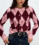 Cardigan corto de punto con estampado de rombos en tonos rosado y bordó, cuello redondo, mangas largas y cierre frontal con botones revestidos.