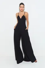 Mono largo negro de punto de viscosa acanalado, con pernera ancha, cintura ajustada, abertura en el busto, tirantes finos y ballenas en la cintura. Se cierra con cremallera en la espalda.