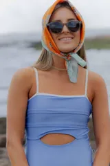 Malla enteriza color celeste con acabado metalizado, diseño cut-out en la cintura y ribetes en color blanco.